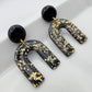 Black arch dangle earrings with gold shimmer