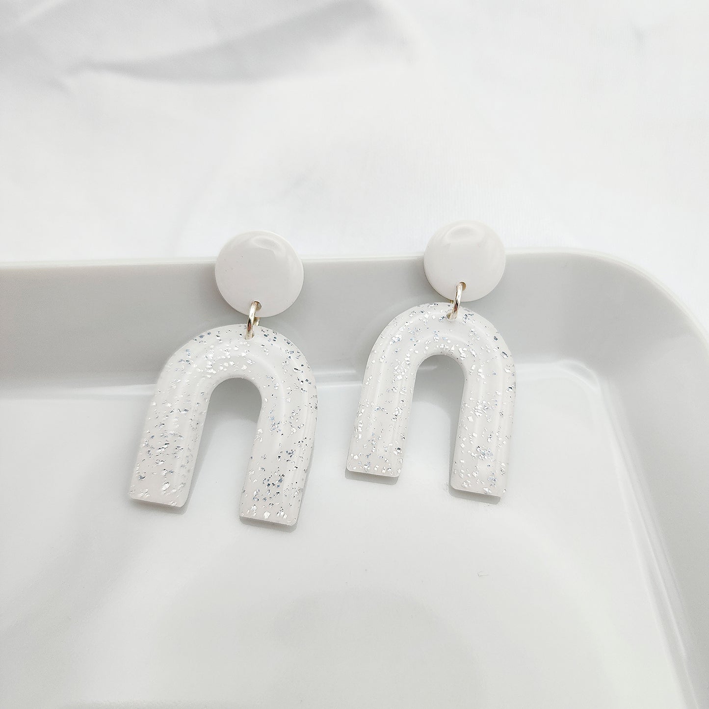 Dangle white arch earrings with silver shimmer