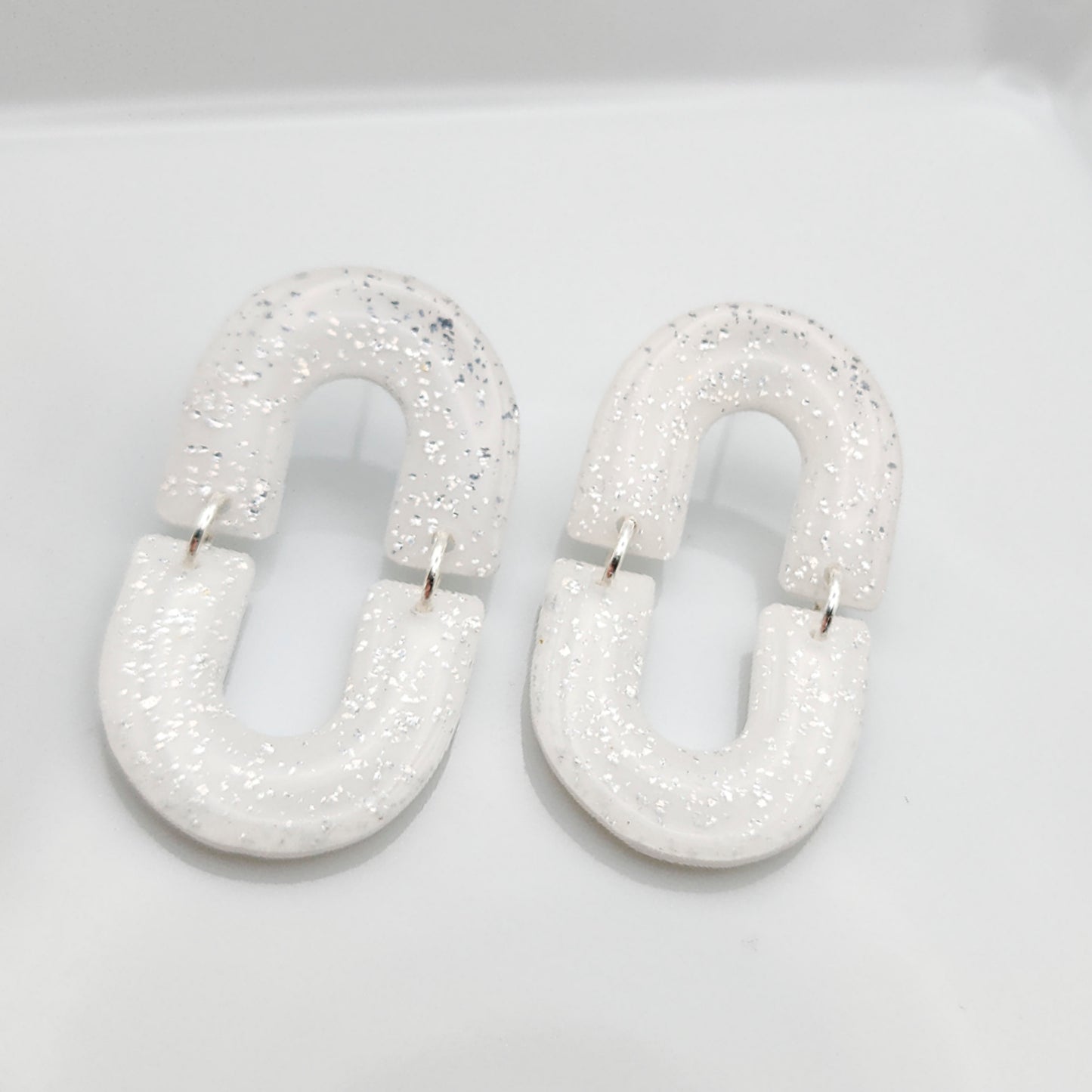 Oval dangle white earrings with silver shimmer