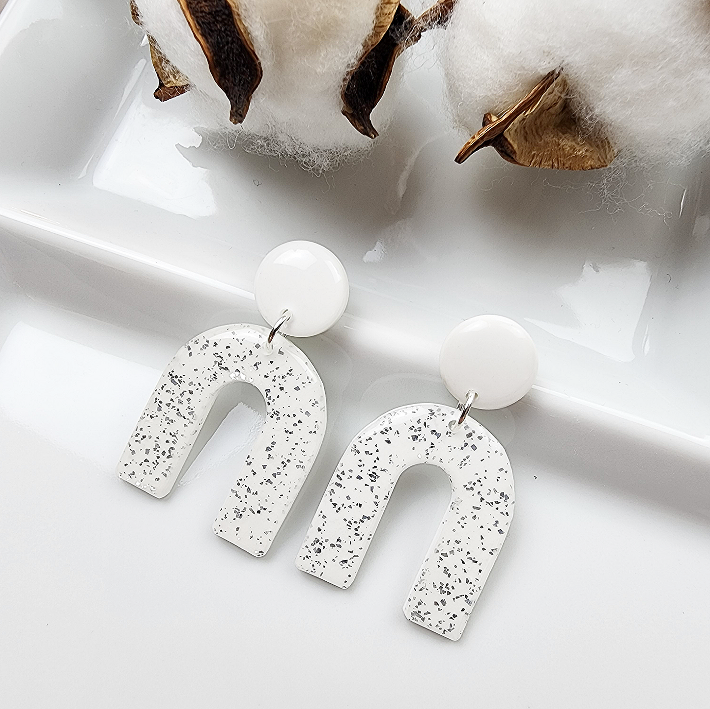 Dangle white arch earrings with silver shimmer